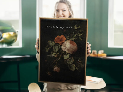Invite deep tranquility and faith into your home with this inspiring Christian canvas wall art. This framed canvas print features a dramatic, dark floral painting paired with the comforting command: “Be still, my soul.”